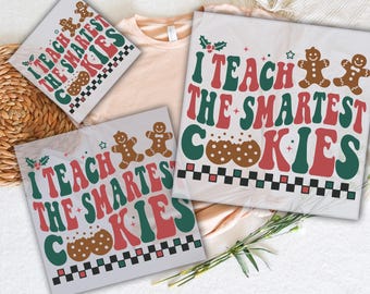 May include: Two iron-on transfers featuring a festive design with the text "I teach the smartest cookies". The design includes gingerbread cookies, holly, and a checkered pattern.
