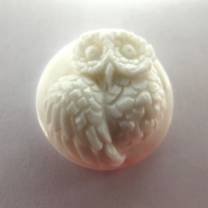 May include: A white carved owl figurine with detailed feathers and eyes. The owl is sitting on a white background.