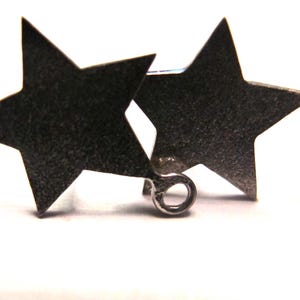 May include: Two silver star-shaped earrings with a small loop on the back of one star.
