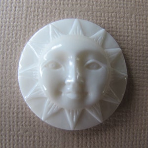 May include: White ceramic sun button with a face and rays.