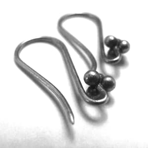 May include: A pair of silver-coloured earrings. Each earring has a curved hook design with three small, round beads clustered at the bottom. The earrings are shown against a white background, with shadows adding depth.