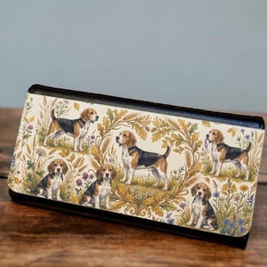 May include: A rectangular wallet featuring a cream-colored exterior with a repeating pattern of beagle dogs, golden wheat stalks, and small wildflowers. The wallet has a solid black border along the top and bottom edges and a fold-over flap closure.