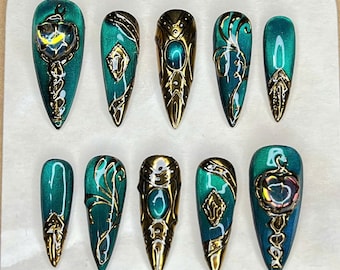 Uñas ojo de gato esmeralda con diseño barroco de espejo dorado.