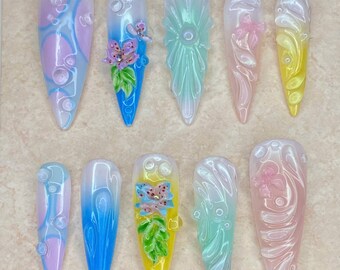 Può includere: Una collezione di dieci unghie finte con vari disegni. Le unghie presentano colori pastello, motivi floreali e astratti e abbellimenti 3D. Il testo "Nail Art" è in alto e il testo "Thank you for your order. I hope you like it." è in basso.