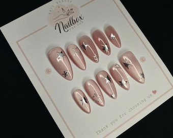 Uñas postizas de almendra y ojo de gato rosa: Diseño de uñas con estrellas plateadas
