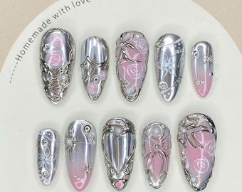 Uñas postizas con degradado rosa y plateado cromado: Arte de uñas con detalles metálicos en forma de corazón en 3D