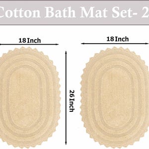 Può includere: Due tappeti da bagno in cotone beige, ciascuno largo 45,7 cm e lungo 66 cm, di forma ovale e con bordo smerlato. Il testo "Cotton Bath Mat Set- 2" è in alto.