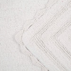 May include: White bath mat with a scalloped edge. The mat is made of a soft, fluffy material.