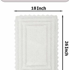 May include: White cotton bath mat with a scalloped edge. The mat measures 18 inches by 26 inches.