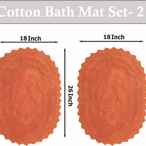 Könnte beinhalten: Zwei ovale, orangefarbene Badematten aus Baumwolle. Jede Matte ist 45,7 cm breit und 66 cm lang. Die Matten haben eine strukturierte Oberfläche und einen gewellten Rand. Der Text "Cotton Bath Mat Set- 2" steht oben.