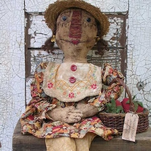 May include: A handmade rag doll with a straw hat, floral print dress, and a basket of fruit. The doll has a painted face and is holding a sign that says "For Sale Today".