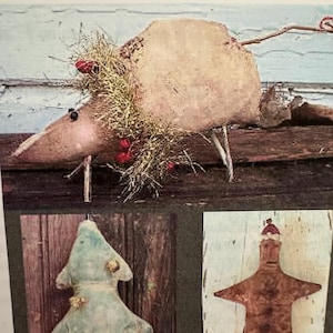 May include: A collection of three decorative figures: a tan mouse with a straw wreath and red berries, a light blue fabric Christmas tree with small gold accents, and a brown gingerbread-style figure wearing a small red hat.