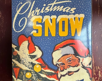 May include: Vintage Christmas snow box with a blue background and white snowflakes. Santa Claus is depicted sprinkling snow on a Christmas tree with red and yellow ornaments. The box reads "Sparkle Christmas Snow".