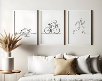 Puede incluir: Tres dibujos en blanco y negro de atletas en diferentes deportes. El primer dibujo muestra a un nadador, el segundo a un ciclista y el tercero a un corredor. Los dibujos están colgados en una pared blanca sobre un sofá blanco con almohadas beige.