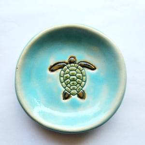 May include: A light blue ceramic dish with a green and brown turtle design.