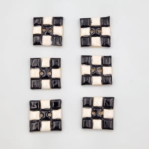 May include: Six black and white checkered ceramic buttons. Each button has two holes.