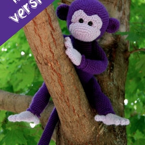 May include: A purple crocheted monkey toy sitting on a tree branch. The monkey has a pink face and a long tail.
