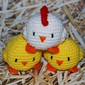 May include: Three crocheted chicks, one white with a red comb and two yellow chicks.