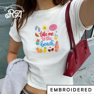 May include: A white ceramic mug with a black handle and the text "But First, Coffee" in a black, handwritten-style font. The mug is on a white surface.