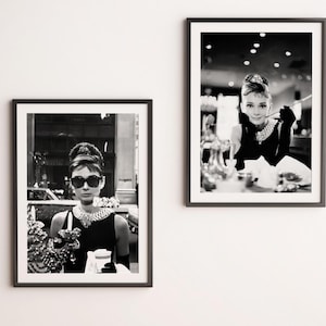 May include: Black and white photo of a woman wearing a black dress, sunglasses, and a pearl necklace. She is holding a cup and looking at the camera.