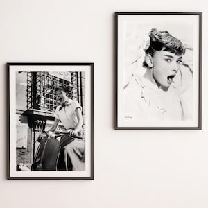 May include: Black and white photograph of a woman riding a vintage scooter. She is wearing a white shirt and a scarf. The photo is framed in a black frame.