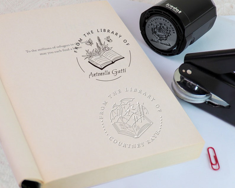 K&ouml;nnte beinhalten: Nahaufnahme eines Buches mit einem individuellen Stempel, der ein offenes Buch mit einem Blumenmuster und dem Text "From the Library of Antonella Gatti" zeigt.