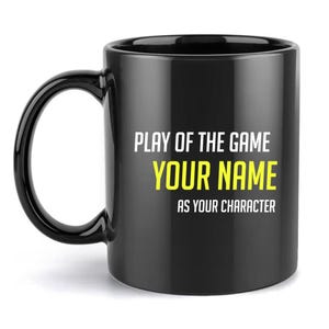 May include: A black ceramic mug featuring white text that reads PLAY OF THE GAME and AS YOUR CHARACTER, with the words YOUR NAME printed in bright yellow in the centre. The mug has a standard handle and a smooth, glossy finish on the exterior.