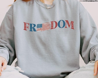 May include: A grey sweatshirt with a distressed American flag design and the word "FREEDOM" printed on the front.