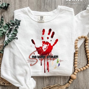 May include: White long-sleeved sweatshirt with a red handprint and the text "NO MORE STOLEN SISTERS" in black.