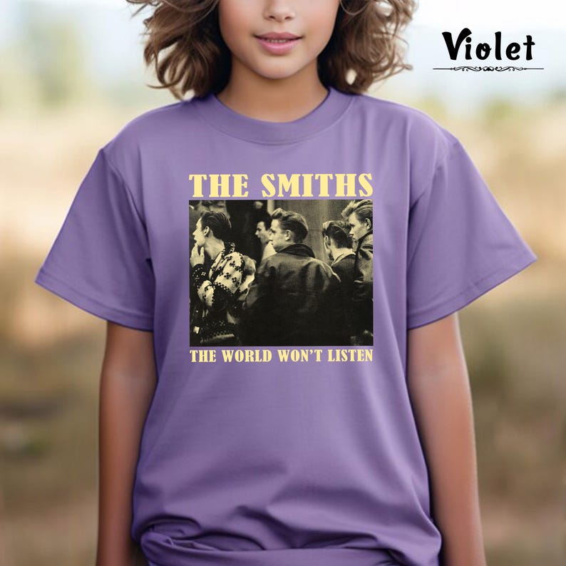 May include: A purple t-shirt with a black and white photo of a band on the front. The band is called "The Smiths" and the text below the photo says "The World Won't Listen."