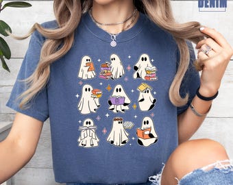 May include: A blue t-shirt featuring a pattern of cartoon ghosts reading books. The ghosts are white with black eyes and are holding books of various colors. The shirt has the text "DENIM DENIM" in the upper right corner.