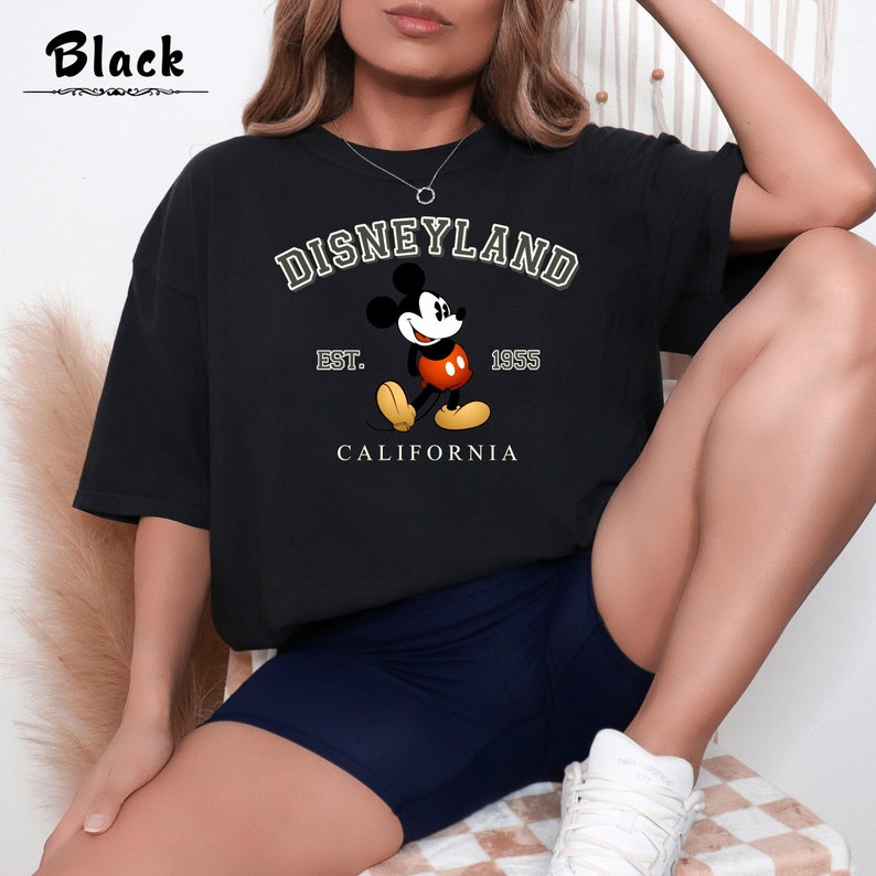 Puede incluir: Camiseta negra con un gr&aacute;fico blanco de Mickey Mouse delante del texto "DISNEYLAND EST. 1955 CALIFORNIA"