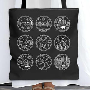 May include: Black tote bag with nine white circular nature illustrations. The bag, shown at 40.6 cm, has black handles and is held by a person in a white dress. A blue and white circular logo is visible in the background.