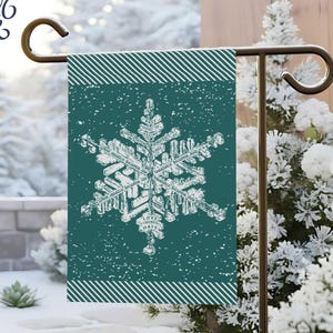 May include: A teal garden flag featuring a white snowflake design. The flag measures 30 x 46 cm and has a striped border. The words "Take a Deeper Look" are in the upper left corner. The word "spruce" is at the bottom.