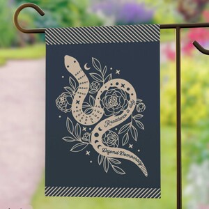 May include: A midnight blue garden flag with a beige snake design and floral elements. The flag has the text "Resistance is Duty" and "Defend Democracy". The design is printed on both sides. The flag is displayed on a metal stand.