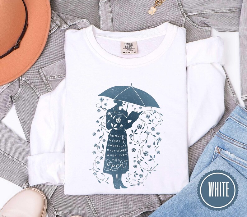 May include: White long-sleeve sweatshirt with a teal graphic of a person under an umbrella reading a book. The graphic includes the text "Books, minds, umbrellas only work when they are open." A white circle with the word "WHITE" is in the bottom right.