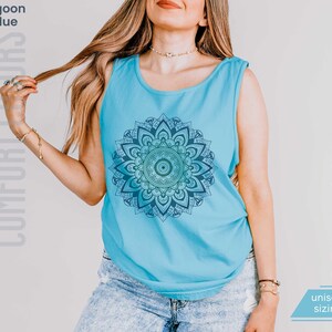 Woman in comfort colors 9360 lagoon blue (medium bright aqua blue) tank top sleeveless tee with mandala graphic in blues and greens. Mandala contains hidden FDT, 8647, RESIST, and symbols of pro-choice.