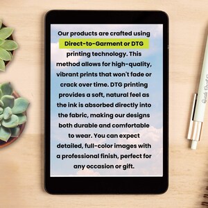 May include: A tablet displays text about Direct-to-Garment (DTG) printing technology, emphasizing high-quality, durable, and comfortable prints. A pen and a succulent plant are on a wooden surface.