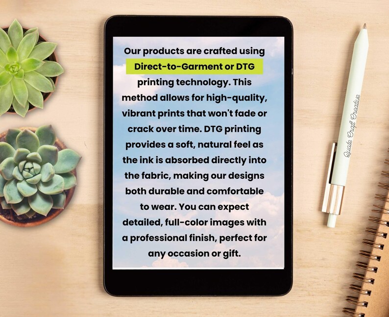 May include: A tablet displays text about Direct-to-Garment (DTG) printing technology, emphasizing high-quality, durable, and comfortable prints. A pen and a succulent plant are on a wooden surface.