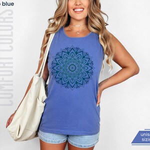 Woman in comfort colors 9360 flo blue (medium bright blue) tank top sleeveless tee with mandala graphic in blues and greens. Mandala contains hidden FDT, 8647, RESIST, and symbols of pro-choice.