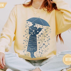 BUTTER (warm pale yellow) model wearing soft sweatshirt with floral umbrella design, ideal for English teachers, book club members, and readers who love comfort and wit