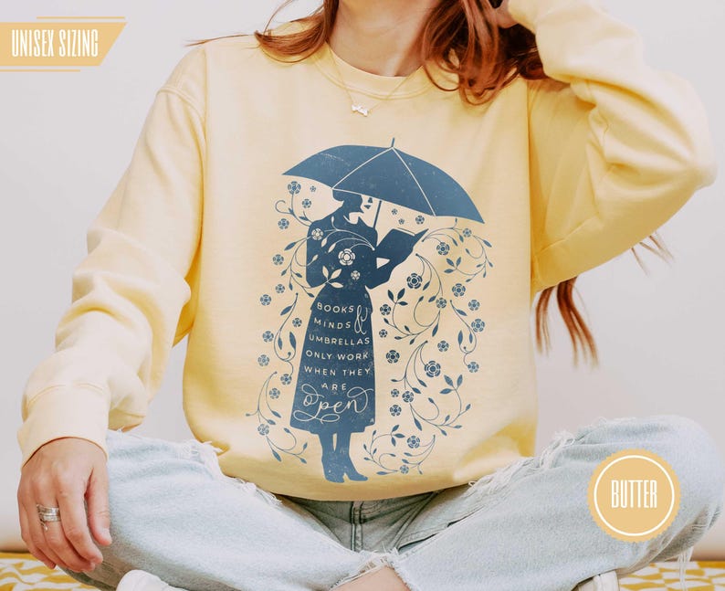 BUTTER (warm pale yellow) model wearing soft sweatshirt with floral umbrella design, ideal for English teachers, book club members, and readers who love comfort and wit