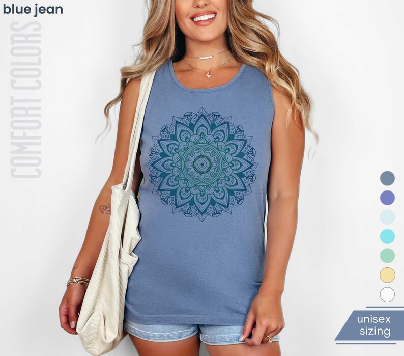 Woman in comfort colors 9360 blue jean (medium muted slate blue) tank top sleeveless tee with mandala graphic in blues and greens. Mandala contains hidden FDT, 8647, RESIST, and symbols of pro-choice.