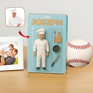 Può includere: Action figure personalizzata di uno chef in uniforme bianca e cappello da cuoco, confezionata in una scatola blu con la scritta "JOSEPH". La scatola include utensili da cucina in miniatura e una palla da baseball.