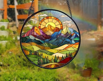 May include: A stained glass window hanging from a chain, depicting a colorful mountain landscape with a bright yellow sun rising over the peaks.