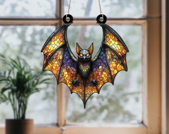 May include: A stained glass bat hanging from a window. The bat is made of yellow, orange, and purple glass with black accents. The bat has glowing red eyes.