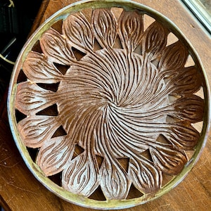 May include: A brown ceramic bowl with a decorative design of swirling lines and cut-out leaf shapes around the rim.