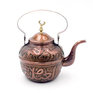 May include: Copper teapot with detailed animal and calligraphy engravings. It has a curved spout, a handle, and a decorative finial. The teapot's design includes embossed images of animals and Arabic script, showcasing a traditional aesthetic.
