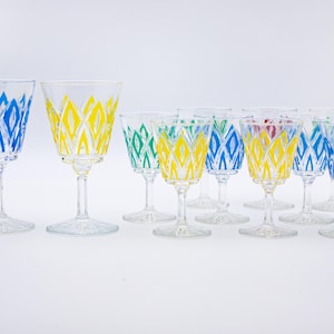 May include: Set of 11 clear glass wine glasses with a geometric pattern in blue, yellow and green. The glasses have a tall, slender stem and a wide bowl.