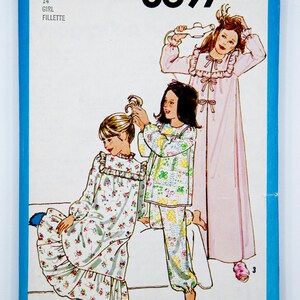 May include: Simplicity sewing pattern number 8697 for a girl's nightgown. The pattern includes three different styles: a long nightgown with a ruffled collar, a shorter nightgown with a ruffled collar, and pyjamas with a floral print.